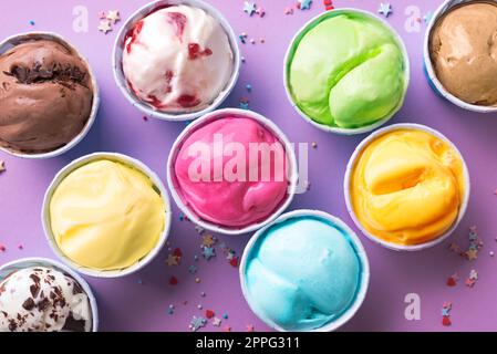 Ice Cream Assortment. Various ice creams or gelato on purple background, copy space. Frozen yogurt  in small cups - healthy summer dessert. Stock Photo