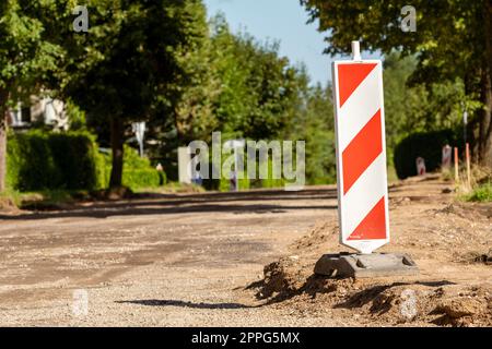 Red and white striped traffic control devices on the road being repaired Stock Photo