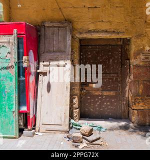 Broken wooden door on orange grunge stone bricks wall in abandoned district Stock Photo