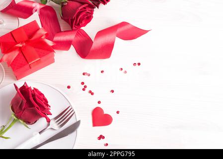 Valentines day table setting, red roses and gift box on white background, copy space. Valentine's day, love dating or romantic dinner concept. Stock Photo