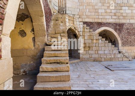 Ancient brick building with two shabby stone stairways and two crumbling arched alcoves on street Stock Photo
