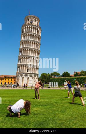 Pisa, Tuscany, Italy - May 23, 2022: Tourists posing in front of the famous Leaning Tower of Pisa. The italian name is Torre pendente di Pisa, at Pisa Stock Photo