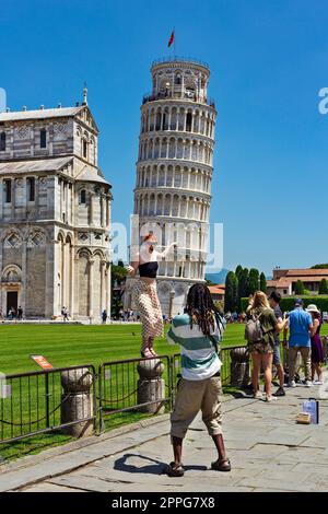 Pisa, Tuscany, Italy - May 23, 2022: Tourists posing in front of the famous Leaning Tower of Pisa. The italian name is Torre pendente di Pisa, at Pisa Stock Photo