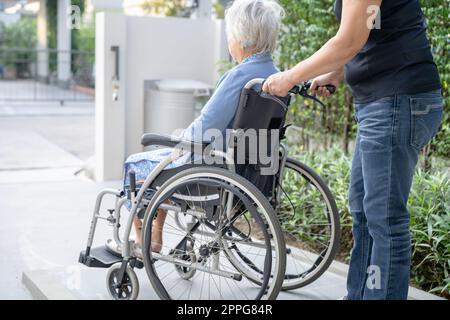 Caregiver help and care Asian senior or elderly old lady woman patient sitting on wheelchair at nursing hospital ward, healthy strong medical concept Stock Photo