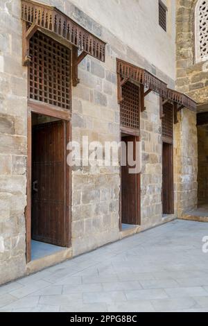 Facade of old abandoned stone bricks wall with three open weathered wooden doors Stock Photo