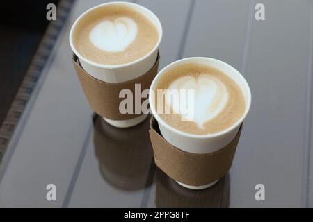 Paper takeaway cups of coffee with cardboard sleeves on glass table, above view Stock Photo