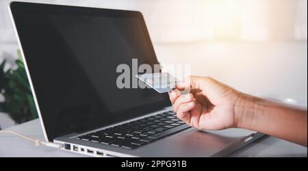 Woman hands holding credit card and using laptop with product purchase at home Stock Photo