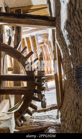 From below shot of aged water mill turning inside weathered mill building Stock Photo