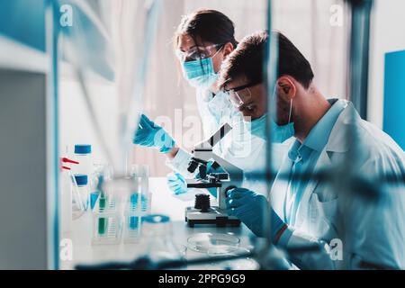 Doctor in the laboratory analyzes samples of codiv-9 under a microscope Stock Photo