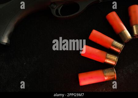 Trigger of a rifle on black background with red lightning with Shotgun shells on a black surface. Ammunition for 12 gauge smoothbore weapons. Hunting ammunition. Dark background. Stock Photo