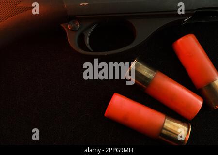 Trigger of a rifle on black background with red lightning with Shotgun shells on a black surface. Ammunition for 12 gauge smoothbore weapons. Hunting ammunition. Dark background. Stock Photo