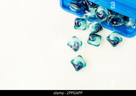 Blue-and-blue washing capsules are scattered on a white background. The process of washing clothes. Liquid washing gel. Stock Photo