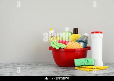 Red basin with cleaning products on marble table. Space for text Stock Photo