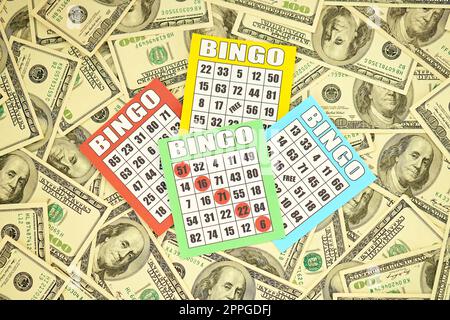 Many bingo boards or playing cards for winning chips and big amount of dollar bills. Classic american or canadian five to five bingo cards on money Stock Photo