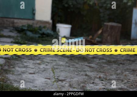 Crime scene tape for covering the area cordon. Yellow tape with blurred forensic law enforcement background in cinematic tone Stock Photo