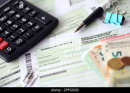 German income tax return form with pen and european euro money bills lies on accountant table close up. Taxpayers in Germany using euro currency to pay taxes Stock Photo