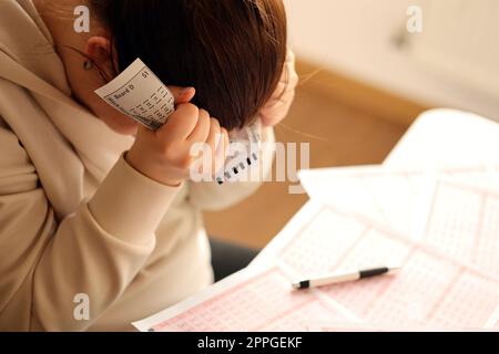 A sad young girl suffers from a loss after looking the unlucky result of the lottery gambling. The concept of losing the lottery and spend money Stock Photo