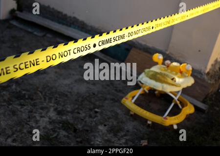 Crime scene tape for covering the area cordon. Yellow tape with blurred forensic law enforcement background in cinematic tone Stock Photo