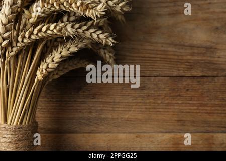 Bunch of dried wheat on wooden table, closeup. Space for text Stock Photo