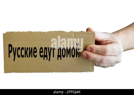 Sign from cardboard in Russian language in one hand with inscription Russians go home Stock Photo
