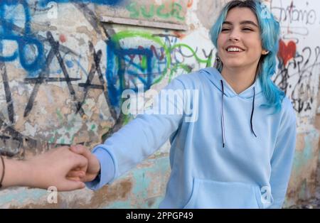 Blue haired young woman wearing hoodie spending time with friends outdoor Stock Photo