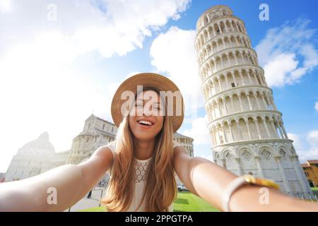 Beautiful tourist girl takes selfie picture with the Leaning Tower of Pisa in Cathedral square, Pisa, Tuscany, Italy Stock Photo