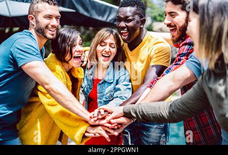 Young diverse friends stacking hands on positive union mood - Multi racial unity culture among students having fun together - Life style friendship co Stock Photo