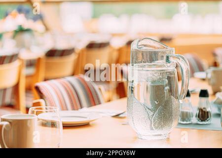 Cozy Interior Of Summer Cafe. Jug Of Icy Cold Ice Water On Table And Cutlery Laid Out Stock Photo