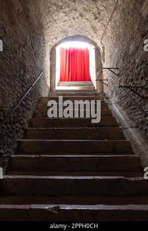 Old corridor with red curtain at the end. Concept for mystery, gothic, escape, hope. Stock Photo