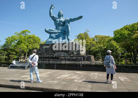 Nagasaki, Japan - April 23, 2023: Tourists in front of the Peace Statue by sculptor Seibou Kitamura in the Peace Park in Nagasaki, Japan. Stock Photo