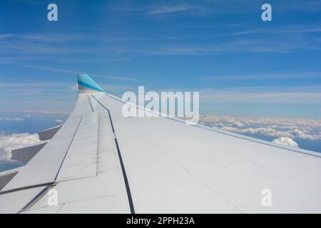 View from an airplane window showing the wing and sky with clouds Stock Photo