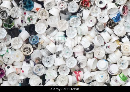 A large number of caps from cans of aerosol paint for graffiti. Smeared with colored paint nozzles lie in a huge pile Stock Photo