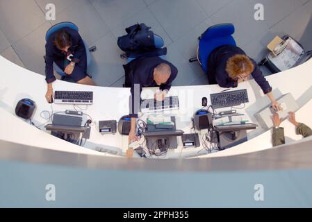 Three customer service agents working at a help desk at the airport. Stock Photo