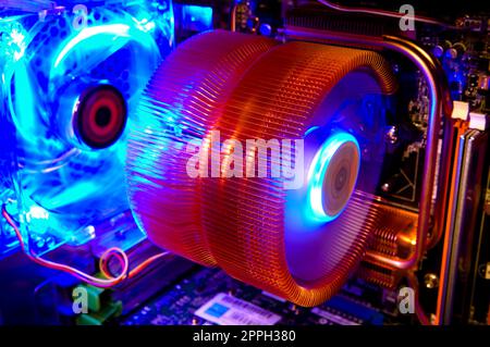 The copper cooling fins and spinning fan of an air cooler in a computer Stock Photo