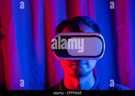 Asian handsome man wear VR helmet excited emotional at home purple and blue background Stock Photo