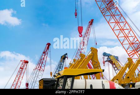 Crawler crane against blue sky. Real estate industry. Red crawler crane use reel lift up equipment in construction site. Crane for rent at parking lot. Crane dealership for construction business. Stock Photo