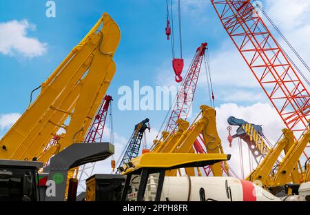 Crawler crane against blue sky. Real estate industry. Red crawler crane use reel lift up equipment in construction site. Crane for rent at parking lot. Crane dealership for construction business. Stock Photo