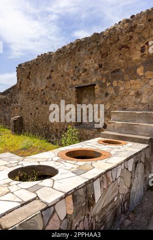 Ruins of an ancient city destroyed by the eruption of the volcano Vesuvius, Naples, Pompeii, Italy. Remains of thermopolium or cook-shop Stock Photo