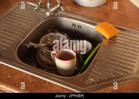 Stack of dirty dishes with food leftovers in the kitchen sink. Unwashed dishes Stock Photo