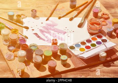 Still life with painted sheet of paper and jars of watercolor and gouache paint Stock Photo