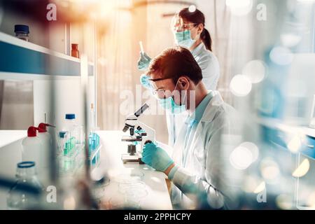 Doctor in the laboratory analyzes samples of codiv-9 under a microscope Stock Photo
