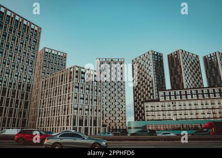 Bottom view of modern skyscrapers in business district against blue sky. Looking up at business buildings, moving transport on the road. Stock Photo