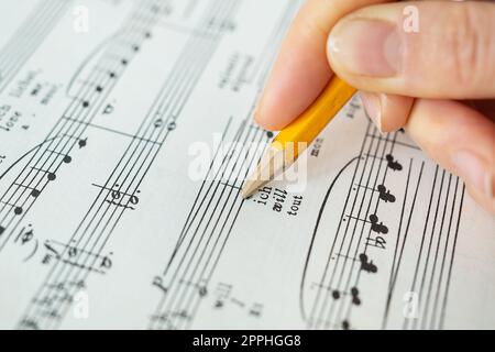 Lviv, Ukraine - December 13, 2022: Piano score, musical notes on paper. The hand makes notes with a pencil on paper. View from above. Stock Photo