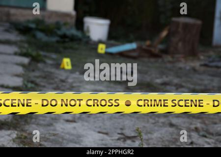 Crime scene tape for covering the area cordon. Yellow tape with blurred forensic law enforcement background in cinematic tone Stock Photo