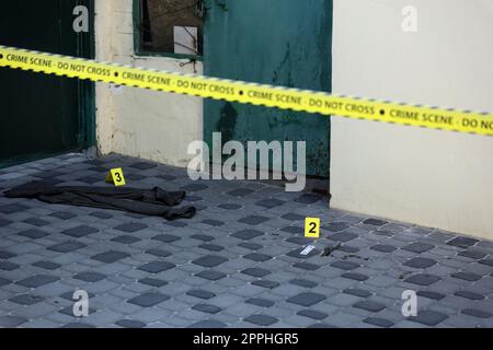 Crime scene tape for covering the area cordon. Yellow tape with blurred forensic law enforcement background in cinematic tone Stock Photo
