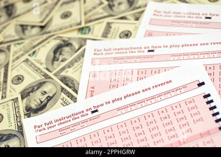 Pink gambling sheets with numbers for marking on big amount of hundred dollar bills. Lottery playing concept or gambling addiction. Close up Stock Photo