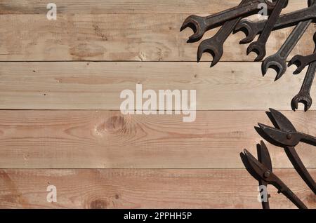 A few rusty spanners and scissors for metal lies on a wooden table in a workshop Stock Photo