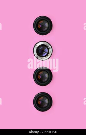 A few camera lenses with a closed aperture lie on texture background of fashion pastel pink color paper in minimal concept. Abstract trendy pattern Stock Photo