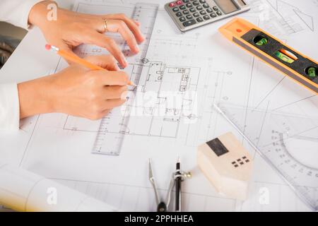 Architect drawing with ruler on house plan blueprint paper for repair tools on table Stock Photo