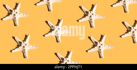 Summer pattern made with white starfish on bright yellow background. Minimal trendy summer concept. Stock Photo